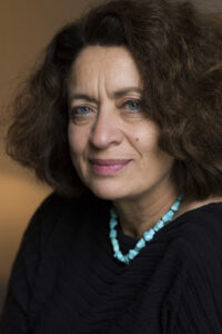 a woman with curly hair wearing a black shirt and turquoise necklace - Dr Ghada Hatem - La maison des femmes